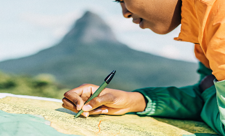 a-person-of-color-leaning-over-a-map–pen-in-hand- (1) a-person-of-color-leaning-over-a-map--pen-in-hand- (1)